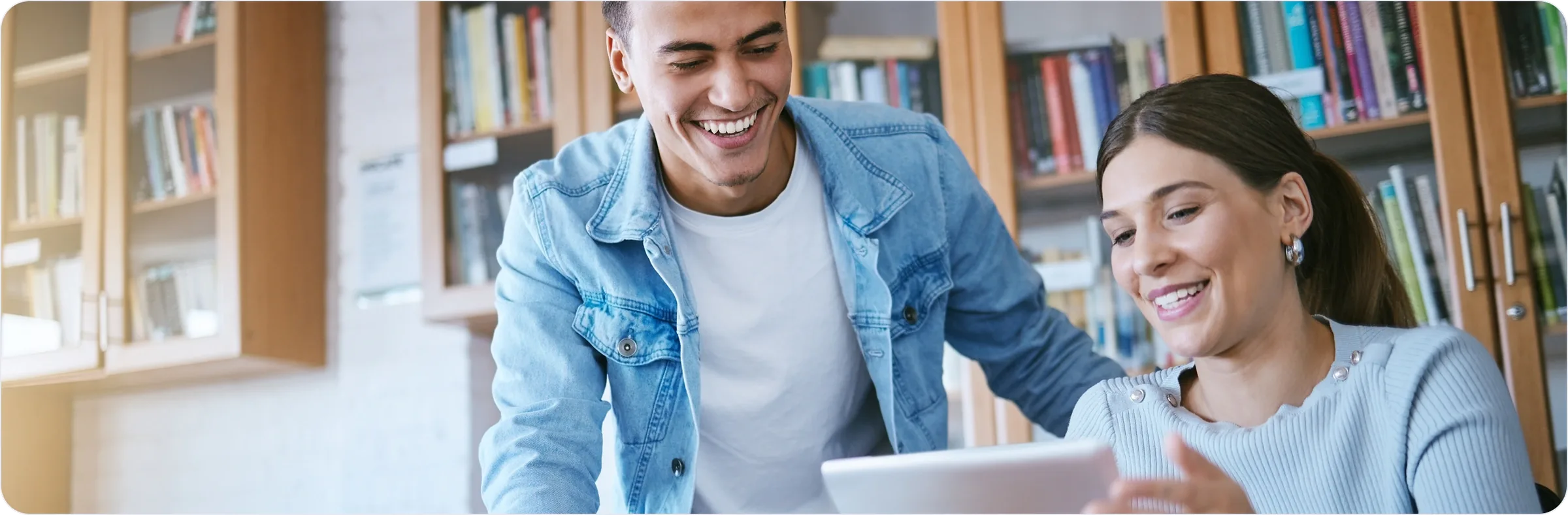 Étudiants échangeant autour d'une tablette dans une bibliothèque